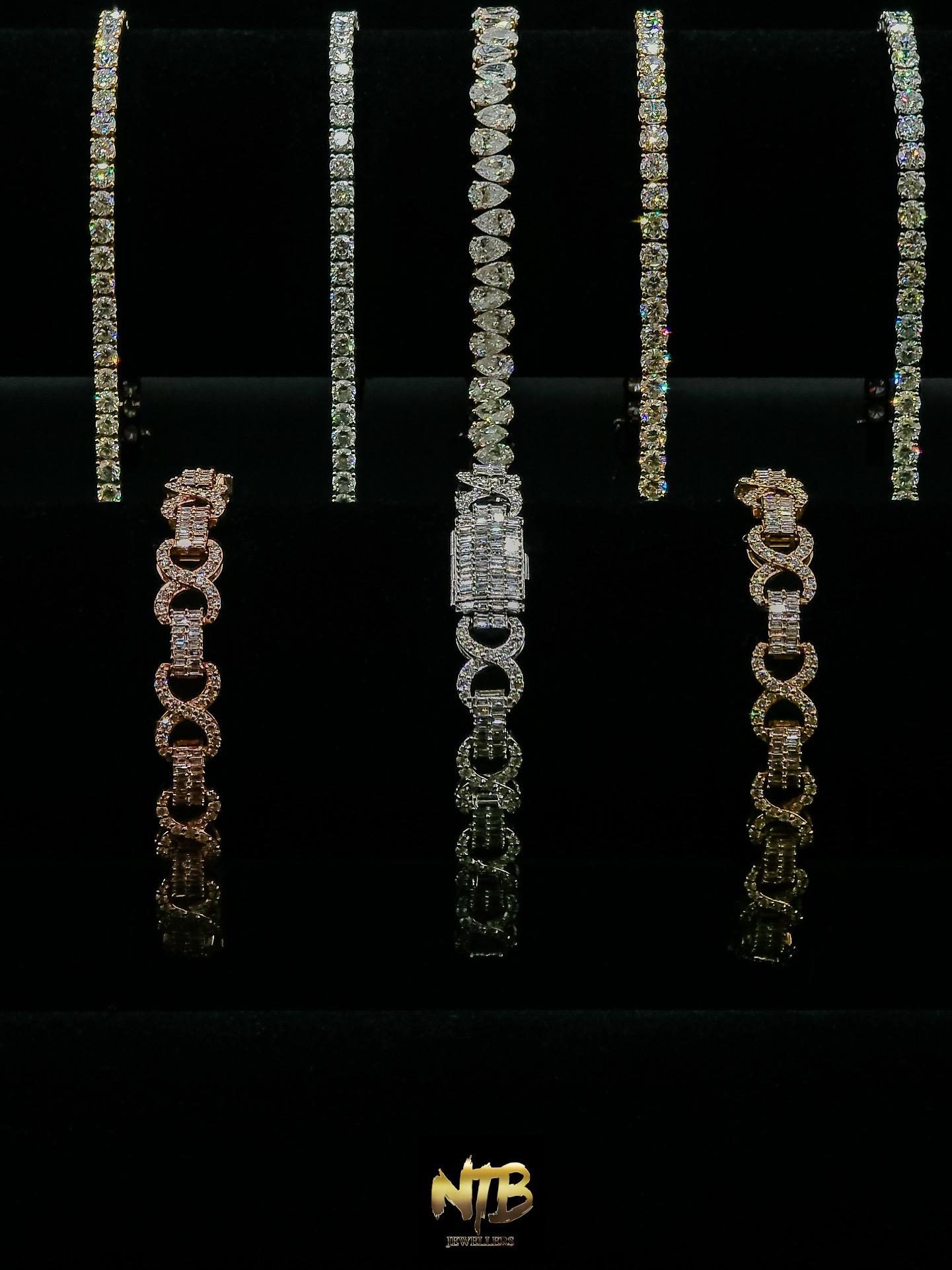 Diamond tennis and infinity-link bracelets displayed on black
